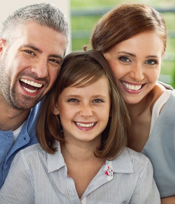 A husband, wife, young boy and young girl smiling for a family portrait.